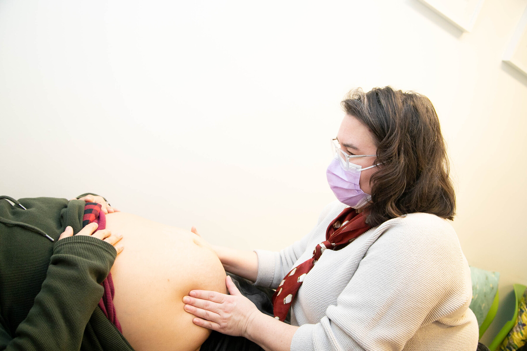 Cheryllee in an examination room. She has her hands on a pregnant woman's stomach, conducting an exam.