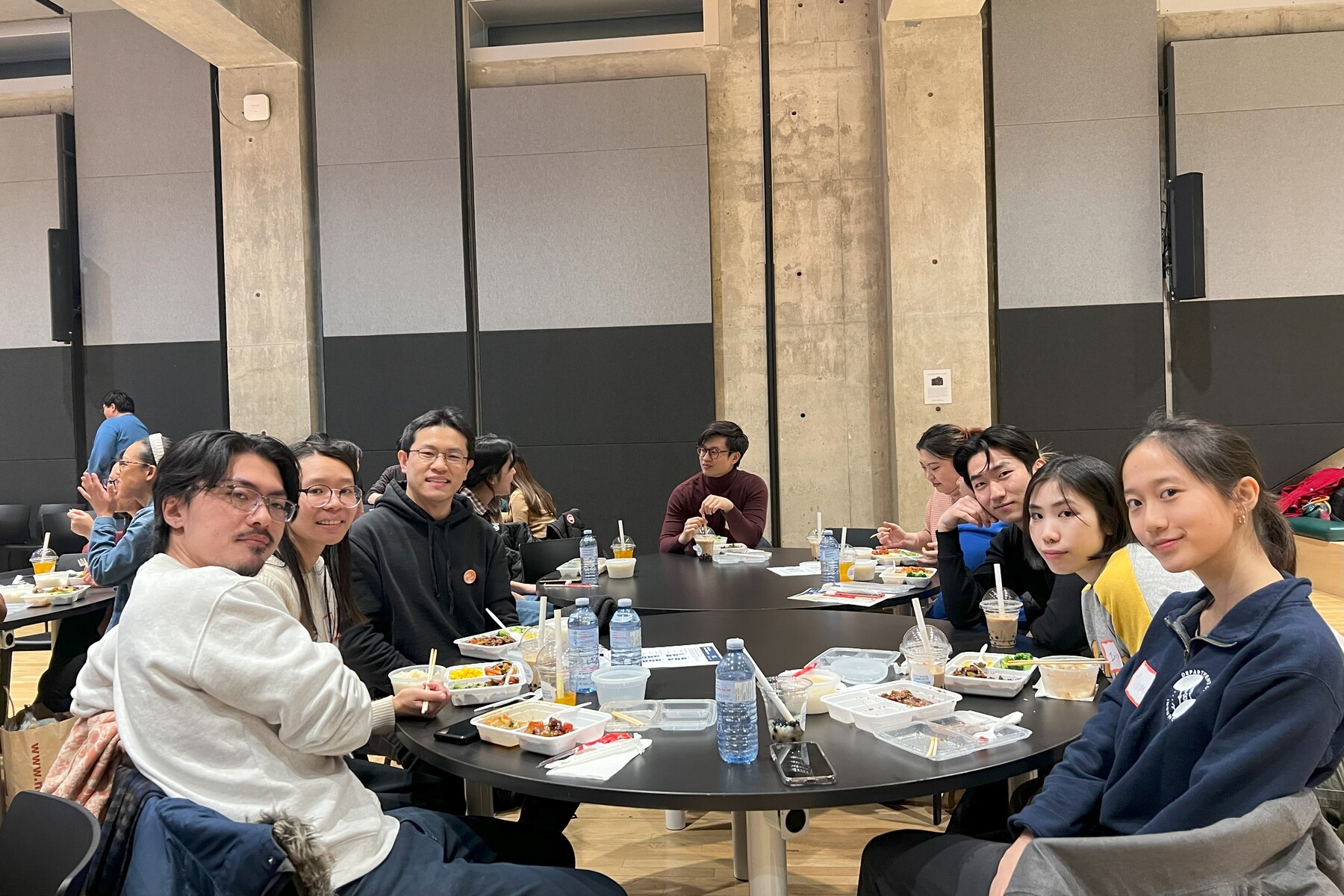A group of people sitting at a round table pose for a photo