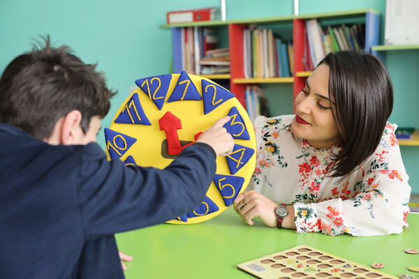 A woman with short dark hair working with a child in an occupational health and safety setting.