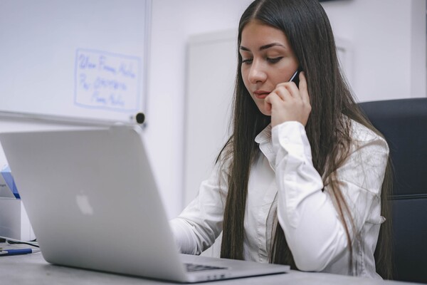 Women using cell phone in front of laptop