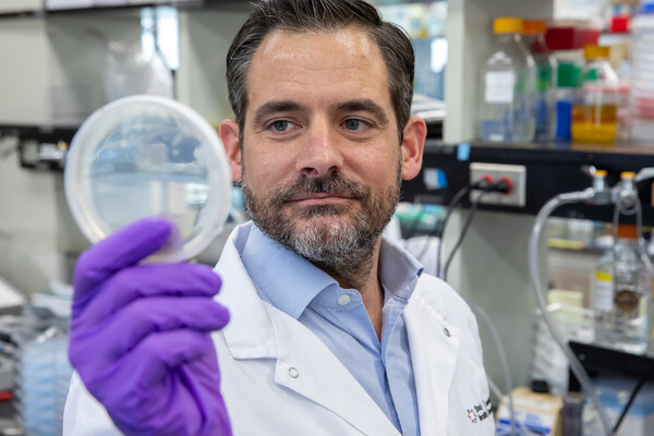 Photo of Daniel Schramek in the lab with petri dish