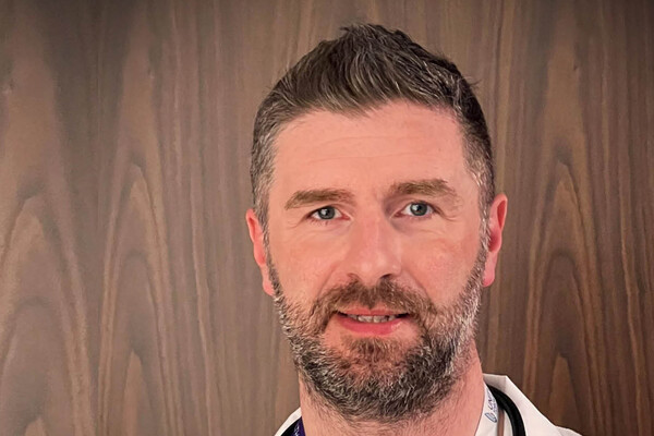 a man with a light brown beard in a white lab coat