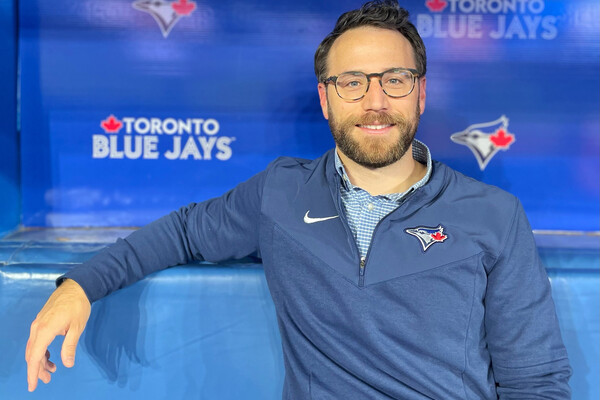 A man sits on a bench with a Blue Jays banner in the background
