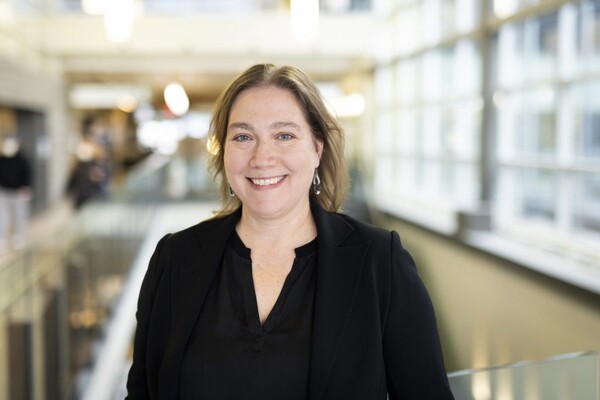 Lynn Mikula stands in a hospital atrium, smiling at the camera