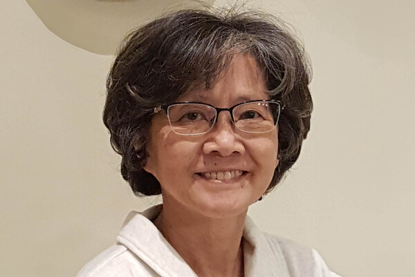 Pamela Mark smiles. She is wearing a white jacket and has dark, curly hair.