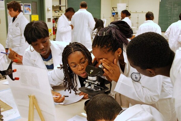 Summer Mentorship Program students look through a microscope.