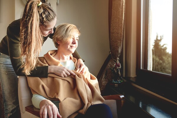 Older and younger woman together by window