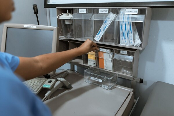 Over the shoulder view of medical professional reaching for item on a shelf