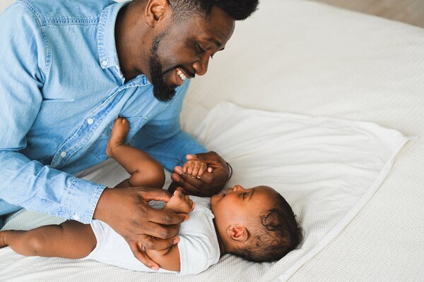 A Glack father smiles lovingly at his infant son.