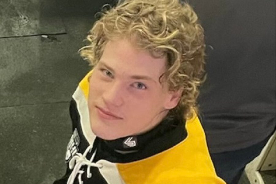 a blond hockey player in a yellow jersey looks up at the camera