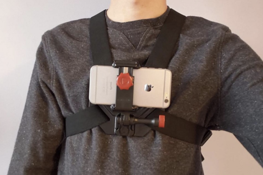An unidentifiable person wears a chest-mounted smartphone