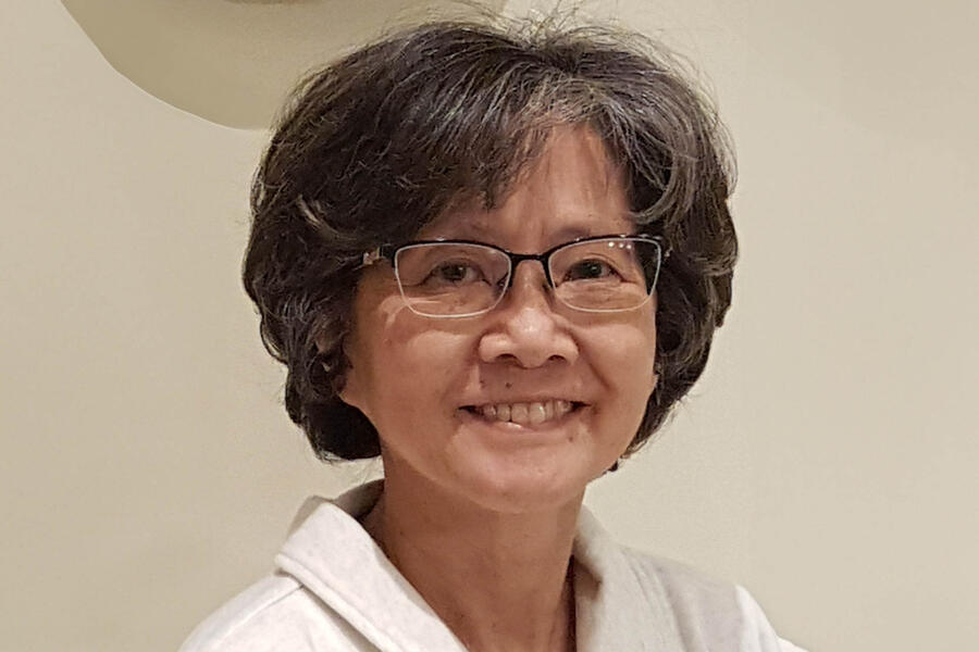 Pamela Mark smiles. She is wearing a white jacket and has dark, curly hair.