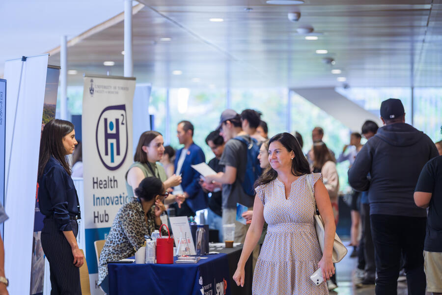 People networking at AcceleratorFest 2024, with the H2i banner in the background.