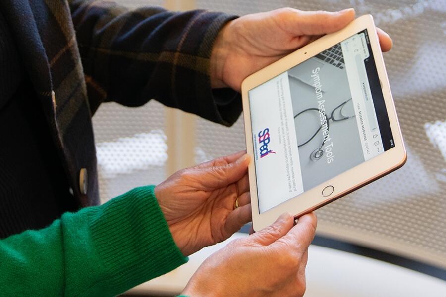 A pair of hands hold a tablet computer displaying the SSPedi tool