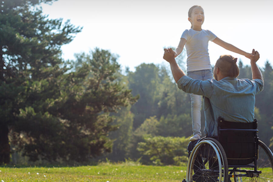 A person in a wheelchair plays outside with a friend.