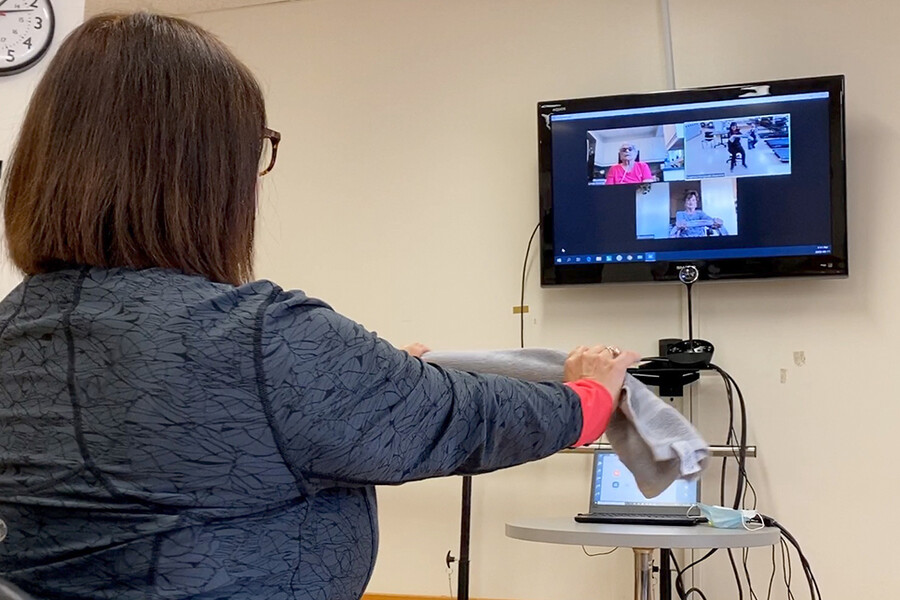 A woman leads a virtual rehabilitation class.