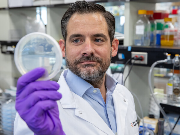 Photo of Daniel Schramek in the lab with petri dish