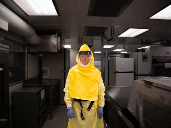 Professor Haibo Zhang wears protective clothing and stands in a containment lab.