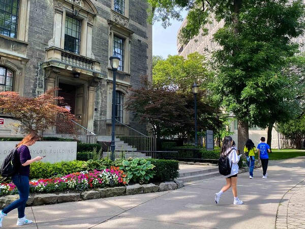 People walk outside the University of Toronto's Naylor Building on an early fall day. 
