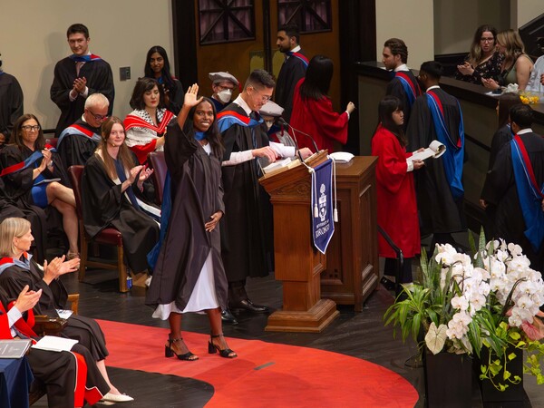 A Temerty Medicine graduate waves to the crowd during spring convocation.