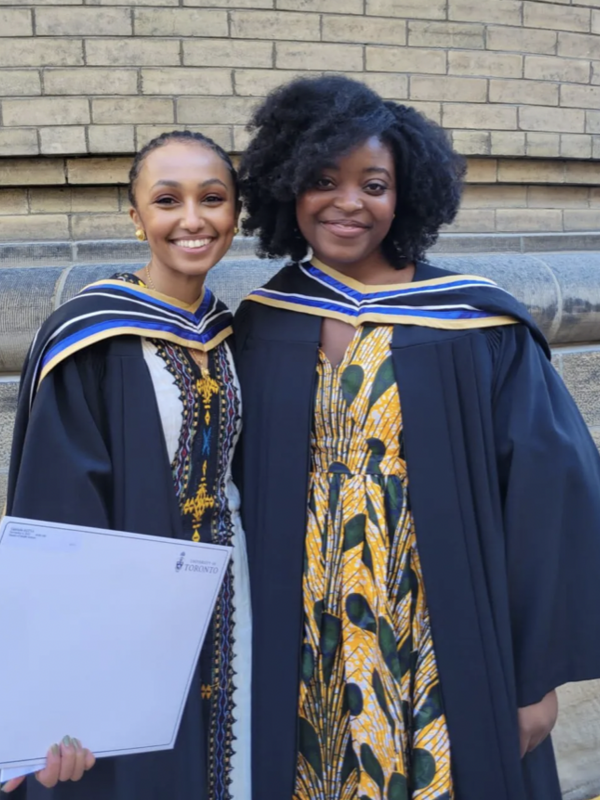 Gabrielle Retta and Gemma Kabeya in their graduation robes outside Convocation Hall.