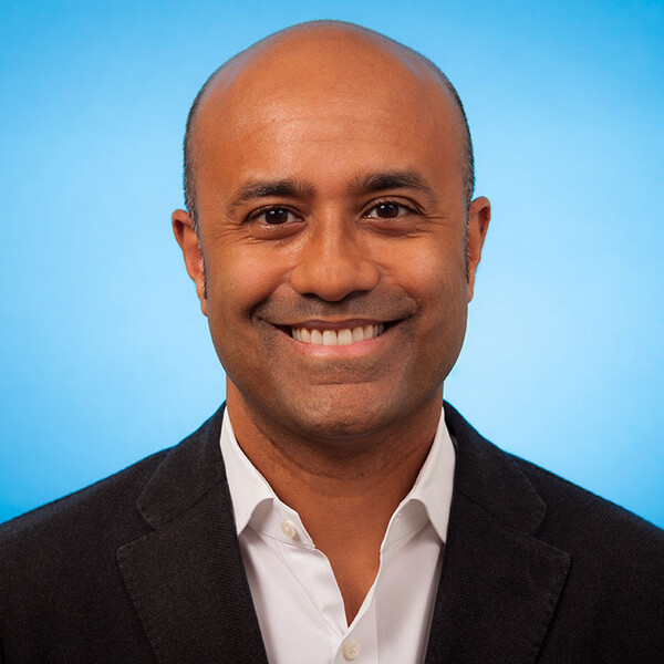 portrait of Sunit Das smiling against a blue background