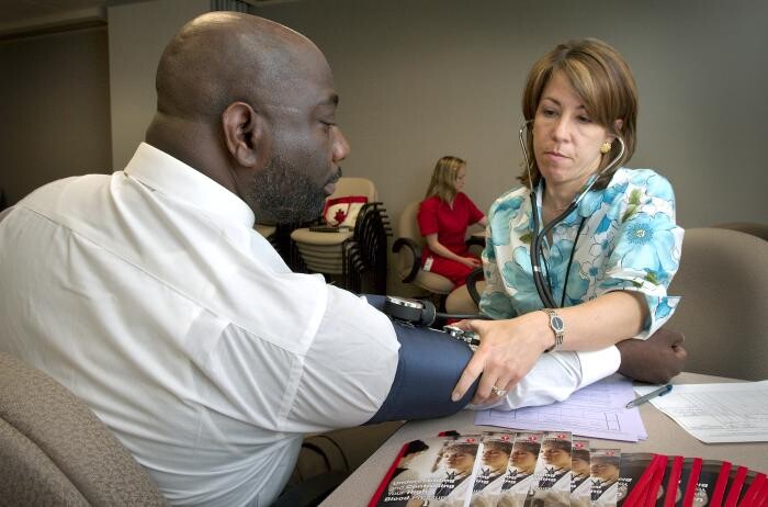 Nurse checks man's blood pressure