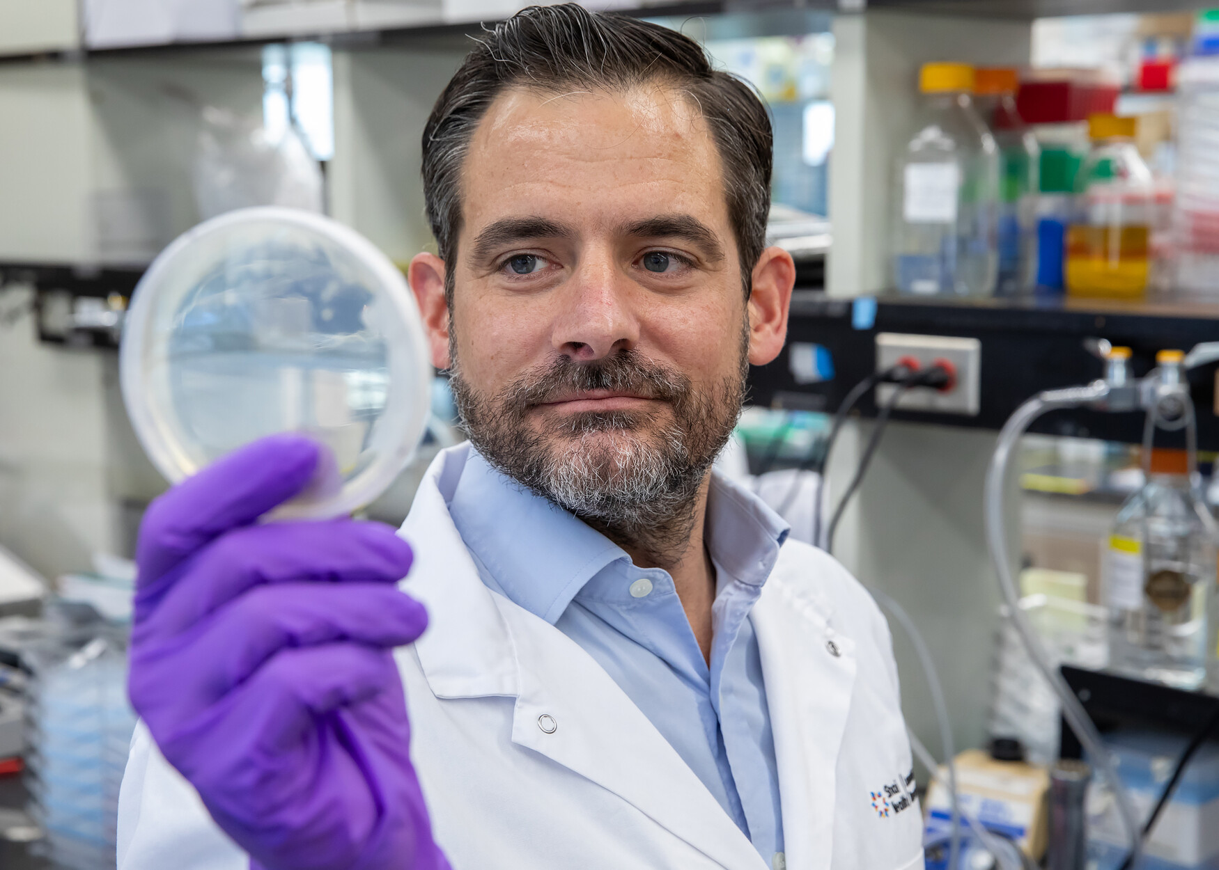 Photo of Daniel Schramek in the lab with petri dish