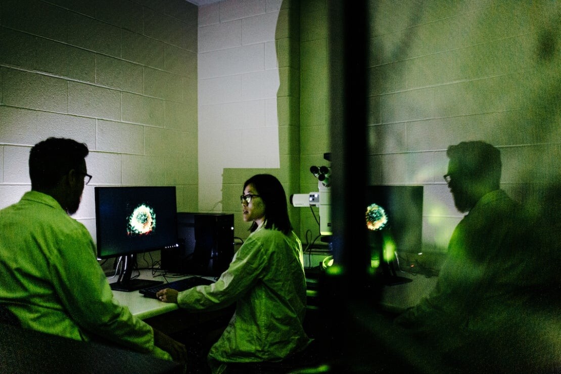 Arthur Mortha, left, and Pailin Chiaranunt work in a darkened lab.