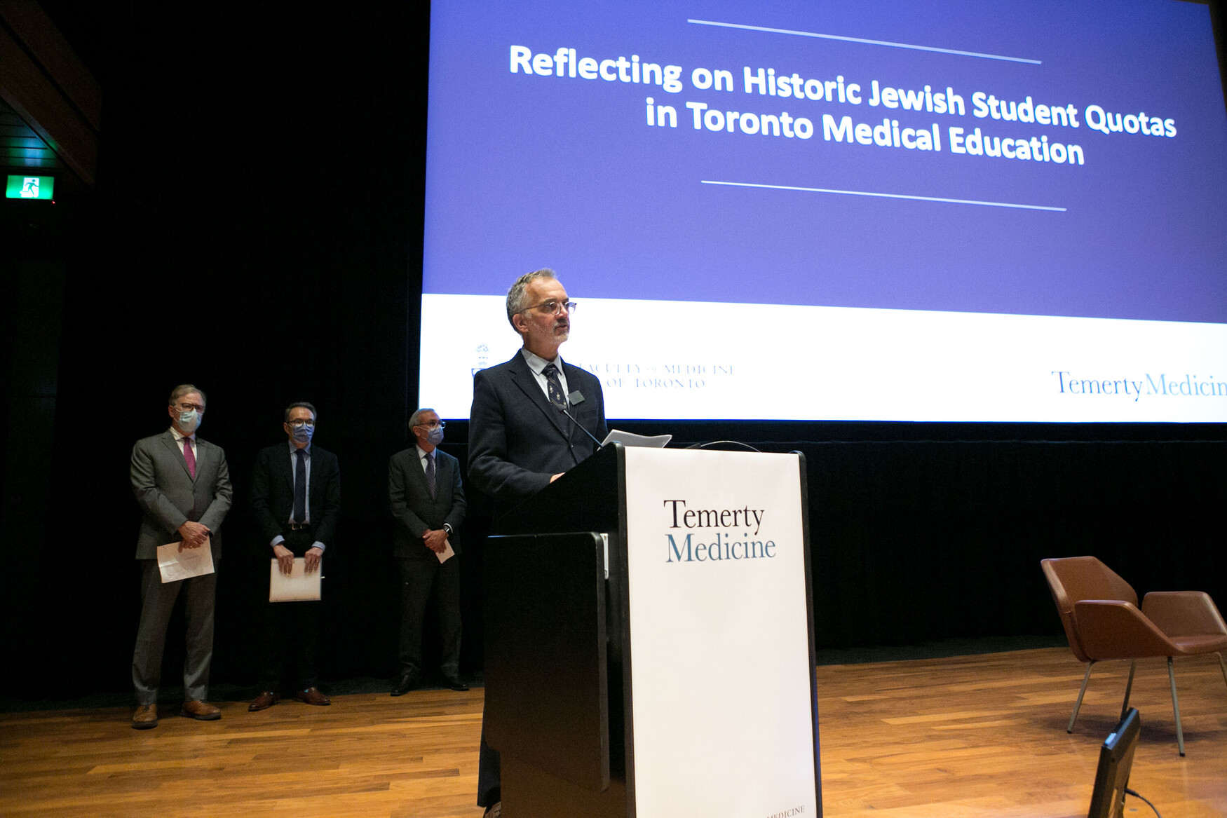 Temerty Medicine Dean Trevor Young speaks at a podium in front of a screen that says, "Reflecting on Historic Jewish Student Quotas in Toronto Medical Education".