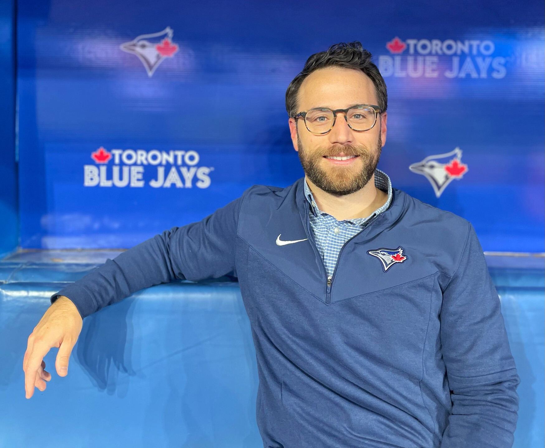 A man sits on a bench with a Blue Jays banner in the background