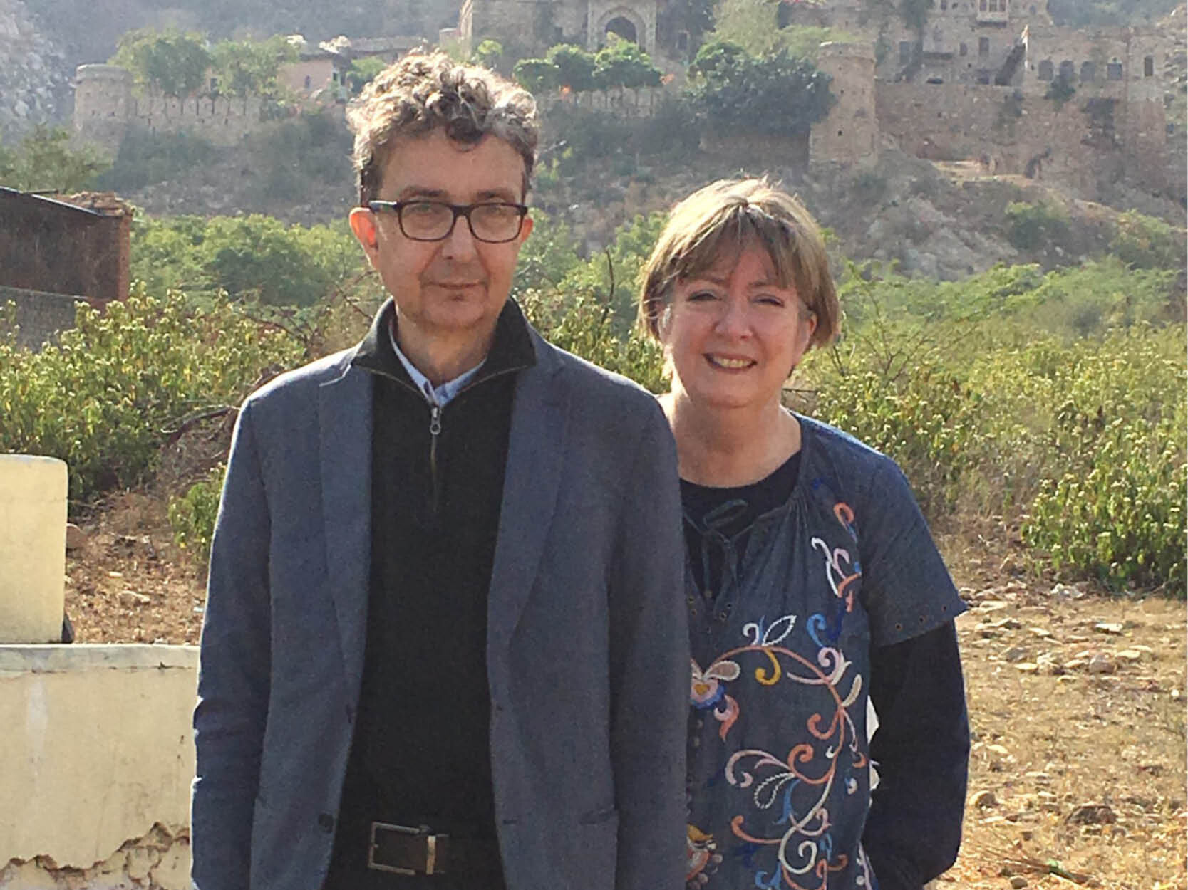 Gerald and Kathy standing side by side. Gerald is on the left in a blue blazer and black sweater, Kathy on the right is in a blue shirt with a floral design.