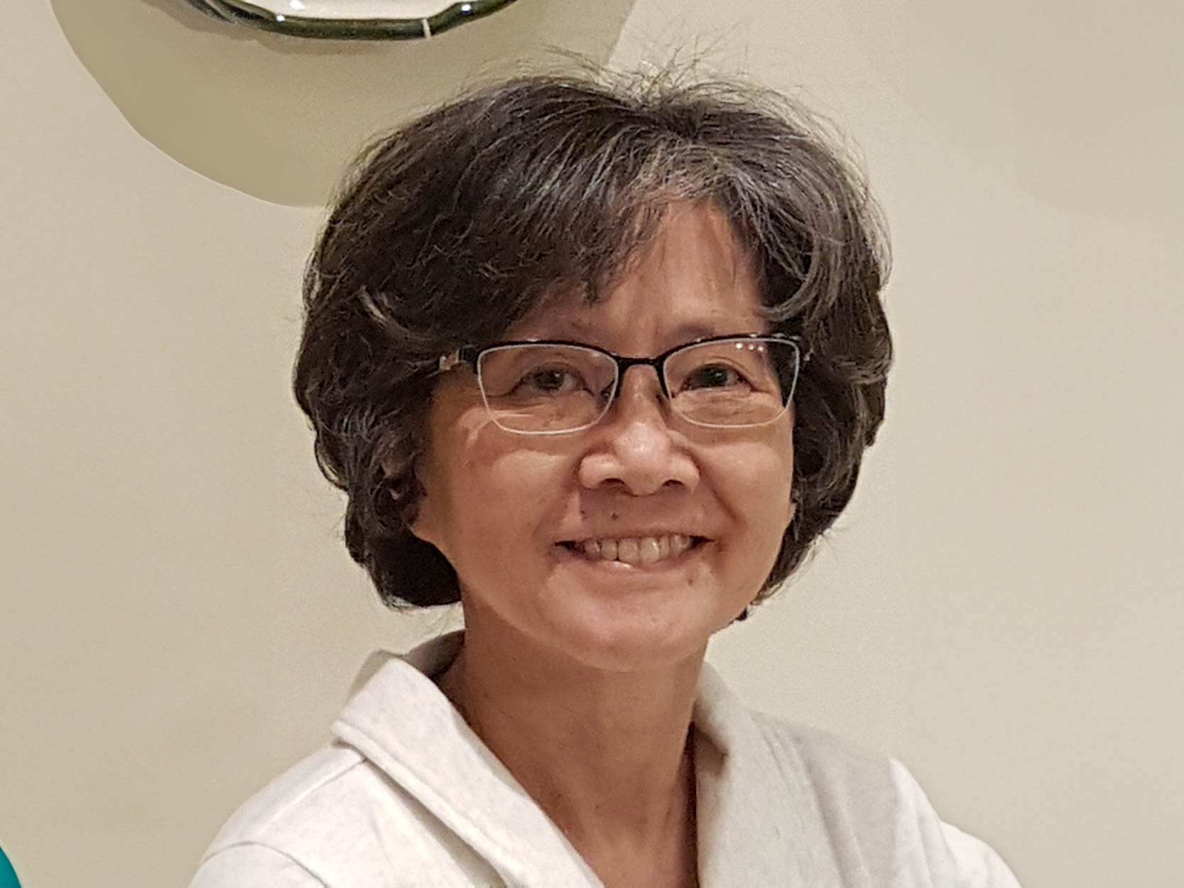 Pamela Mark smiles. She is wearing a white jacket and has dark, curly hair.
