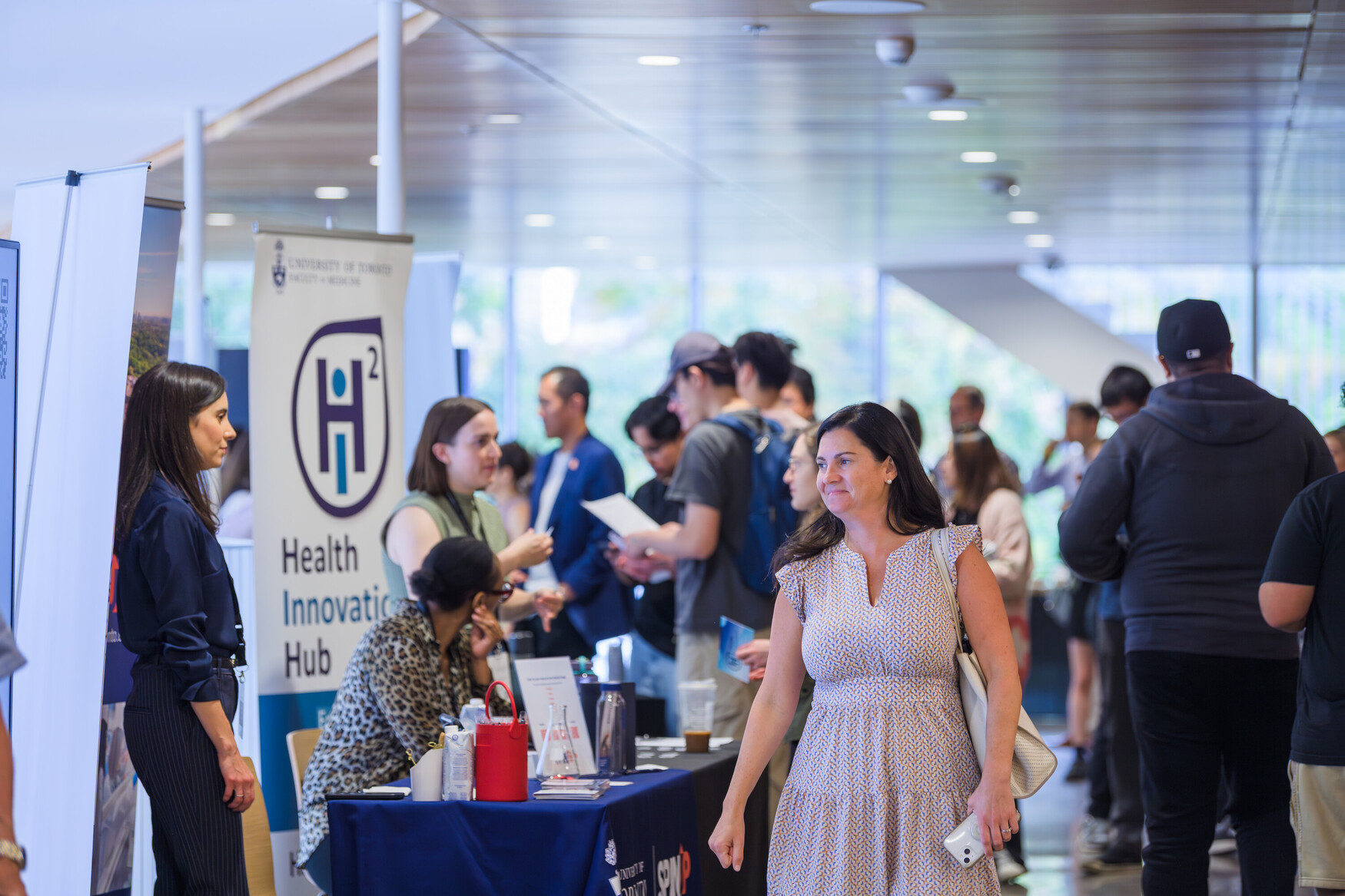 People networking at AcceleratorFest 2024, with the H2i banner in the background.