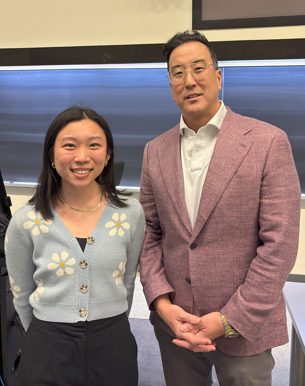 A young woman and a male teacher in a classroom smile into the camera