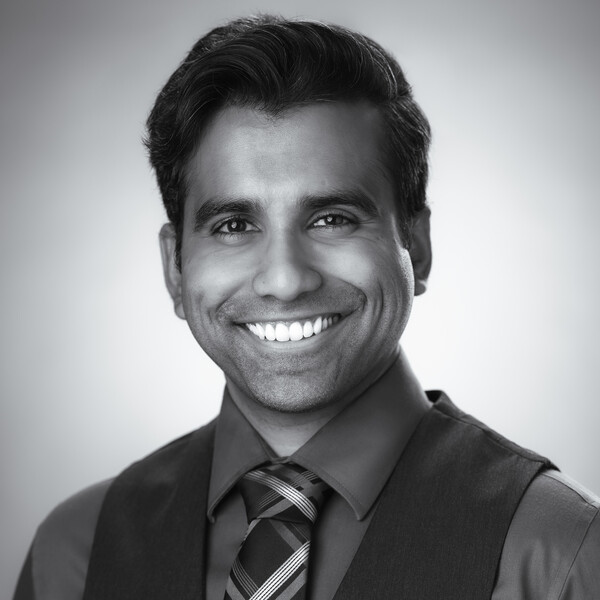 a black and white portrait of a researcher in a suit vest and tie