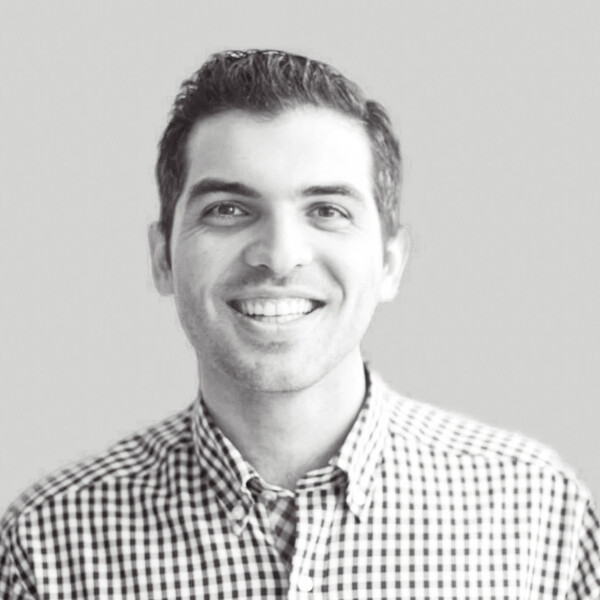a black and white photo of a researcher in a checkered collared shirt with short cropped hair
